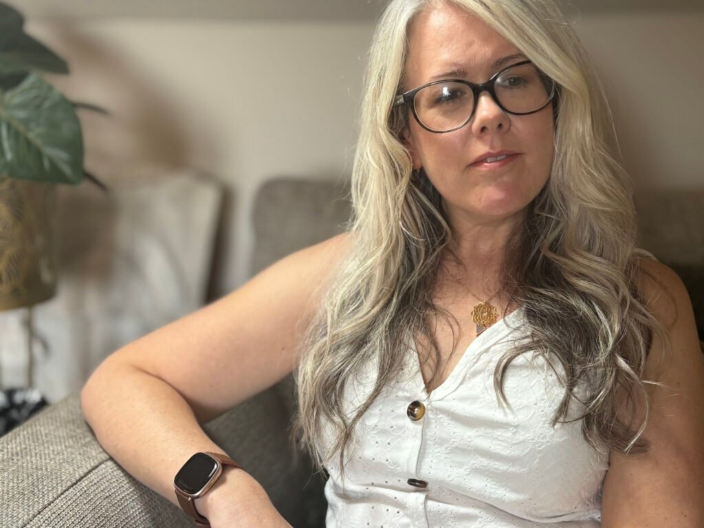 Laura from Laura Heslop Therapy sitting on a sofa looking into the distance